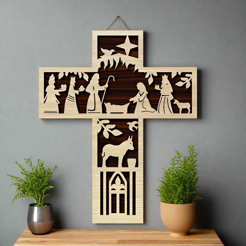 A wooden cross with a manger scene engraved on it, hanging on a wall above a potted plant and a metal vase with a decorative item.