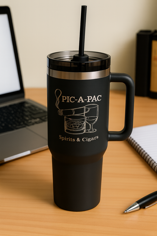 Black travel mug with handle and straw lid on a desk with laptop and notebook