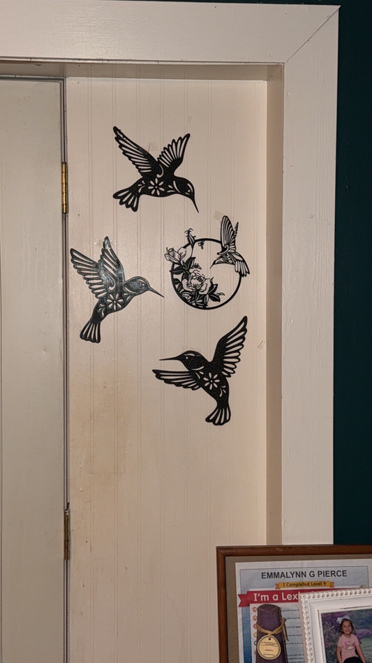 Three 3D printed hummingbirds and one circular floral hummingbird wall decoration arranged on cream beadboard wall paneling