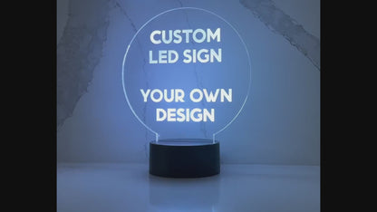 acrylic lighted led sign on a black round base with lights illuminating the words Custom LED sign at the top and YOUR OWN DESIGN on the bottom of the circular piece of acrylic..